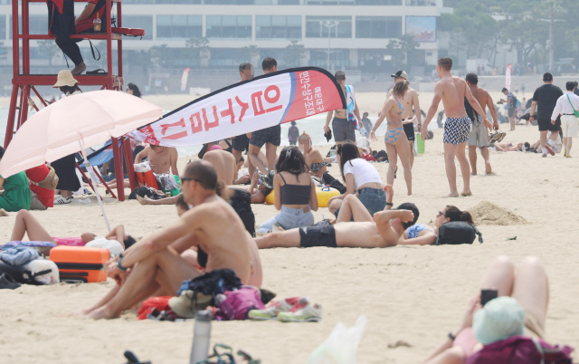 한낮 최고 기온이 29도까지 오르며 한여름 같은 날씨를 보인 11일 오후 부산 해운대구 해운대해수욕장에 피서객들이 태닝을 하며 시간을 보내고 있다. <연합뉴스>